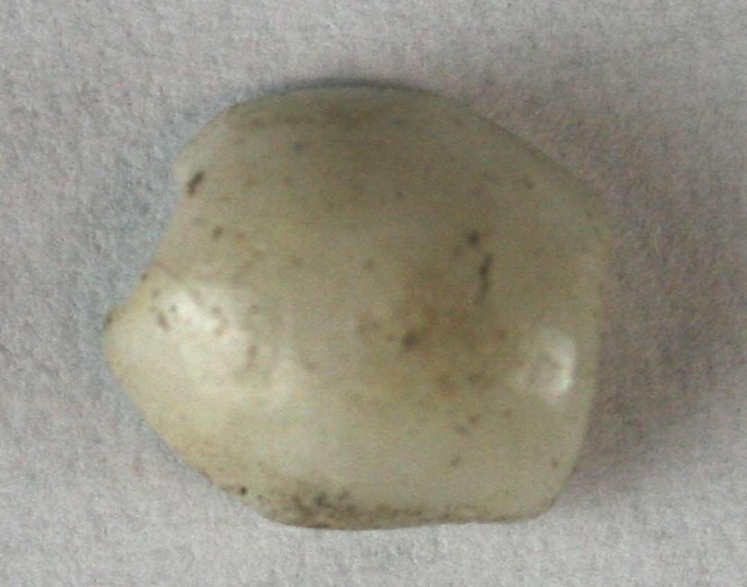 ½ perle spaltet på langs af let dobbeltkonisk form og af grålig ugennemsigtig glasmasse. 9 mm.