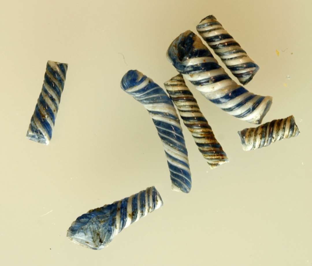 7 fragmenter af tovsnoede glasstænger af varierende tykkelse enkelte let krumme, af blåligt gennemsigtigt glas, der på ydersiden er omviklet med tråde af hvidlig ugennemsigtig glasmasse i S-snoet form.
