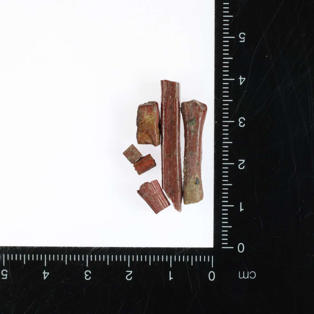 6 fragment stykker af glasstænger med varierende tykkelser af uregelmæssig kvadratisk tværsnitsform, alle af rødbrunlig ugennemsigtig glasmasse.
