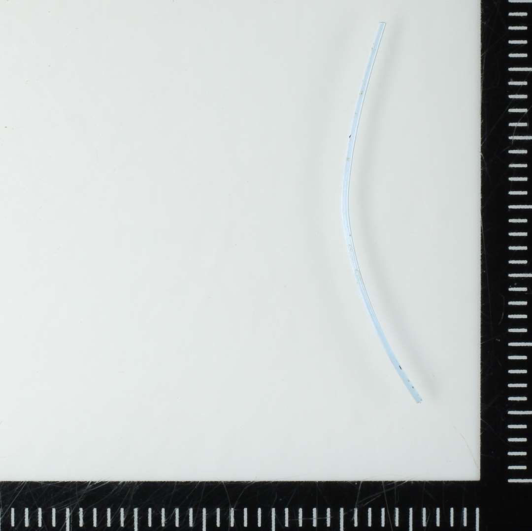 1 let krummet glastrådsfragment af synålstykkelse og af svagt blåligt gennemsigtigt glas. L: 2,8 cm.
