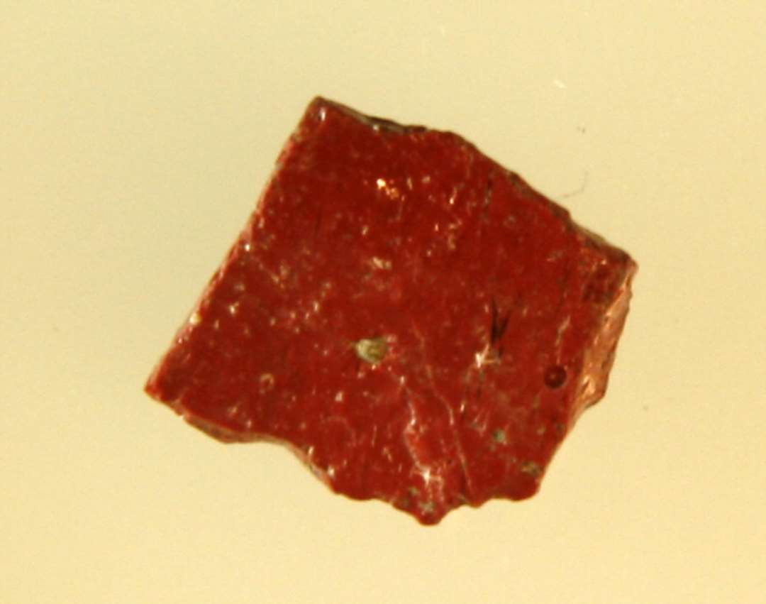 1 fragmenteret mosaikstift af rødbrun ugennemsigtig glasmasse.