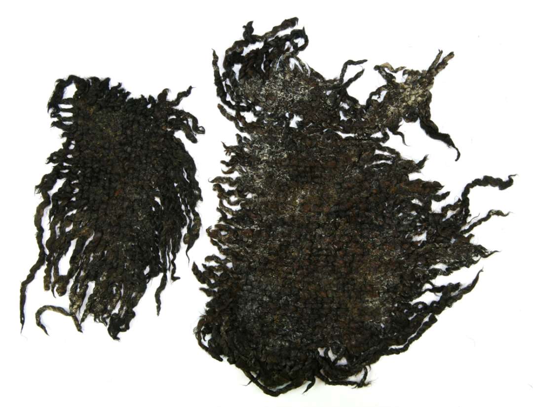 To stykker groftvævet tekstil. Mål h.h.v.: 20.5x16 og 14,5x9 cm.