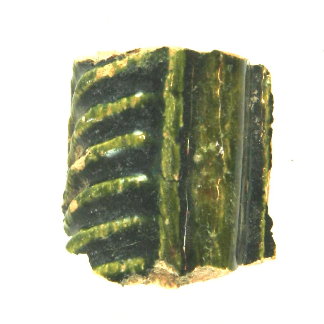 fragment af grønglaseret kakkel. Største mål: ca. 3,5 cm.