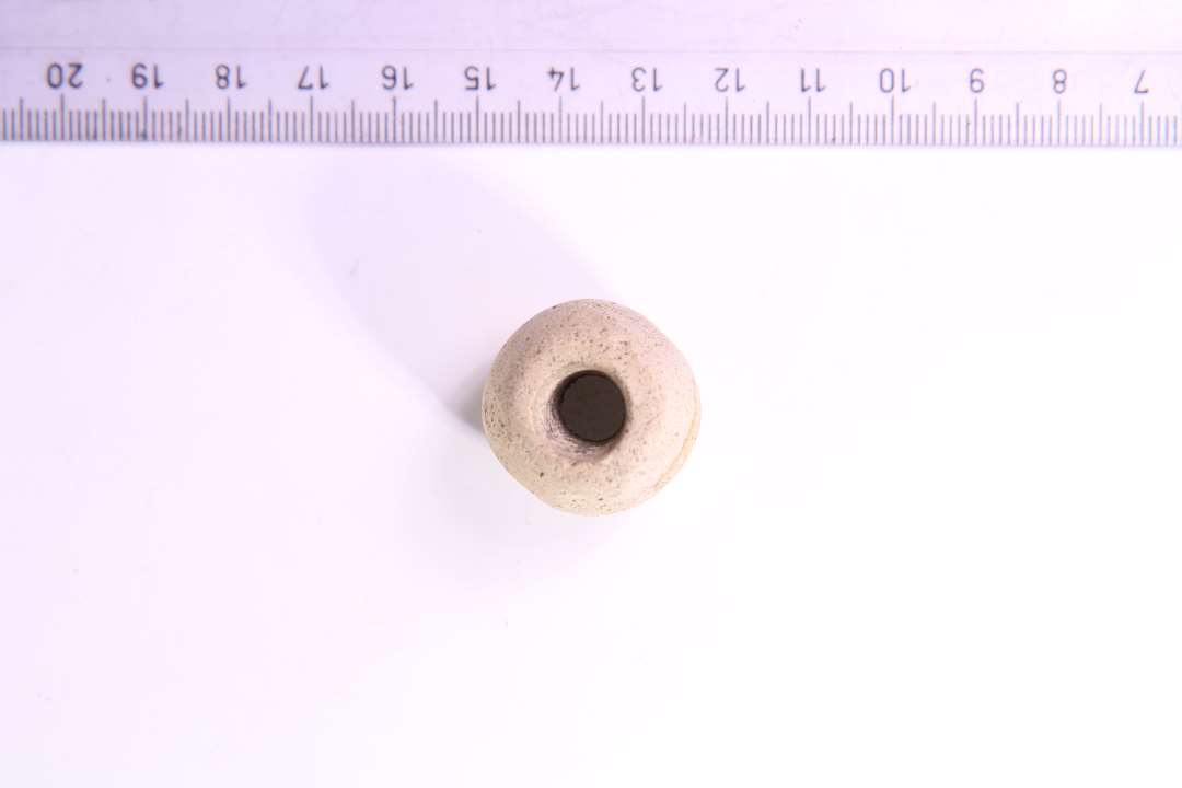 Gullighvidt, fint magret ler. H: 2.1 cm. Største diameter: 2.5 cm. Hullets diameter: ca. 0.8 cm.