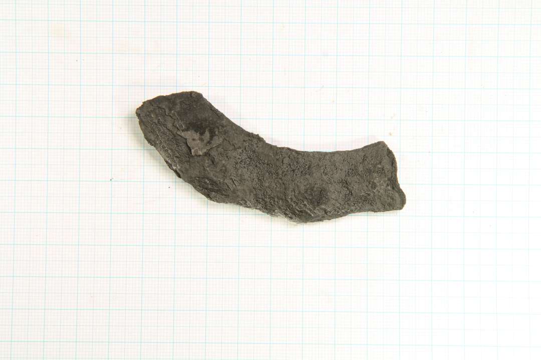 Fragment af hestesko med tre huller. Svagt bølget yderrand. Spansk type. Glødet og voksbehandlet