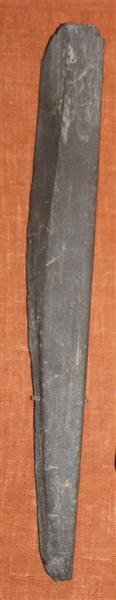 Fragmenteret, stangformet hvæssesten af grålilla skifer. Stenen har nærmest trapezagtig tværsnitsform i den bedst bevarede ende med slibespor på de tre af siderne. Længde : 26 cm. Bredde ; 3,2 cm. Tyk : 1,8 - 9 cm.