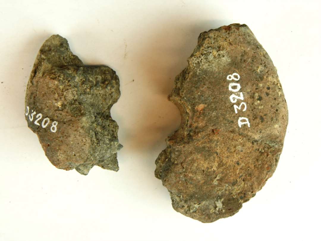 2 hønseægstore fragmenter af discosformet vævevægt af brændt ler. Største mål: ca 7 og 9 cm.