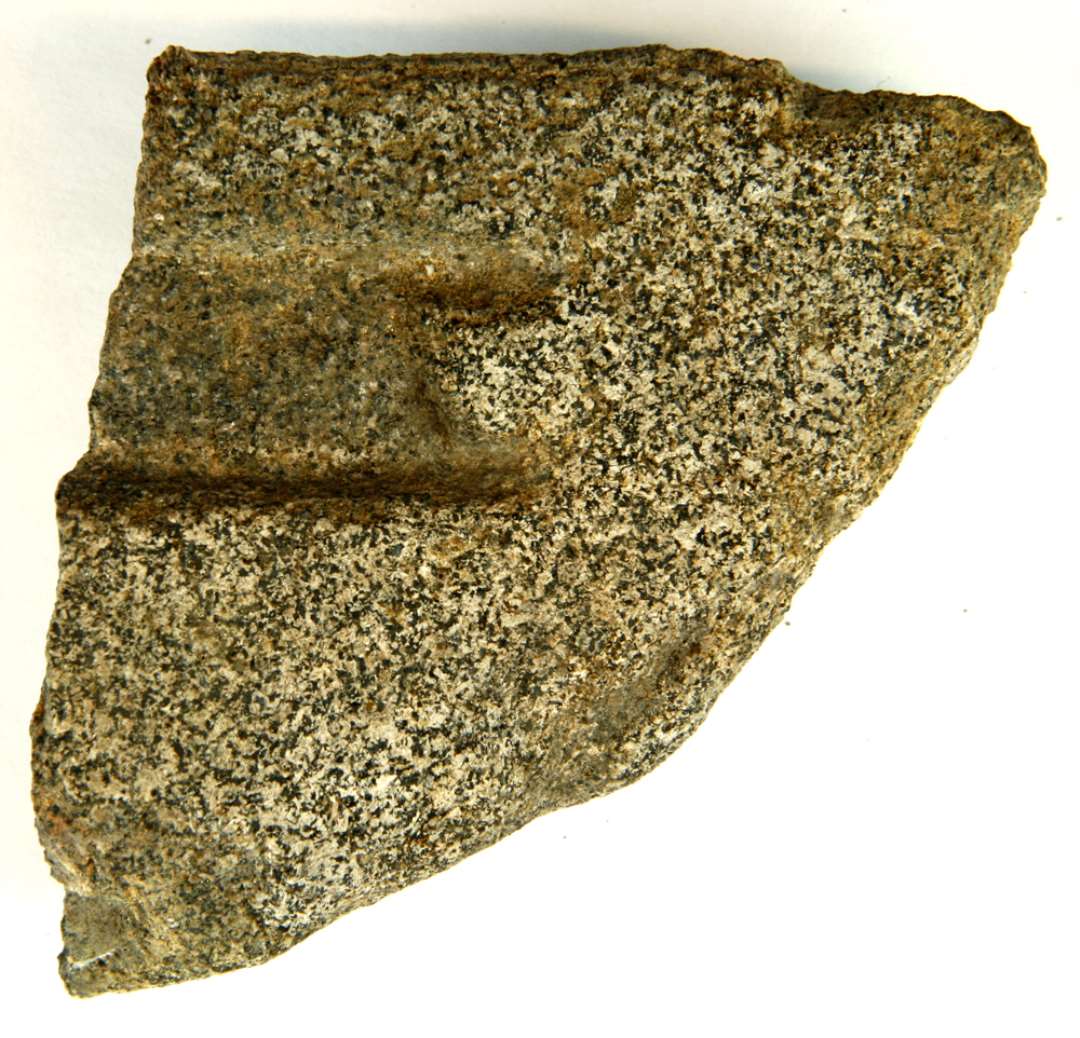 Støbeformsfragment af  et finkornet stykke bjergart, som udgør et fragment af større sten med to omtrent plane sider, hvori er indhugget forskellige paralelle furer af større og mindre dybde.  Længde: ca. 9,5 cm. Bredde: ca. 8,5 cm. Tykkelse: 5,3 cm. på midten 3,3 cm. ved kanten.