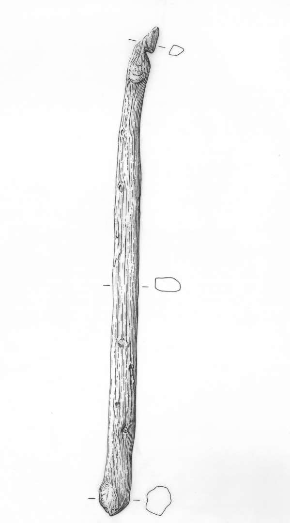 1 groft tilskåret træpind af taks. Rektangulær tværsnitsform med klumpformig afslutning i den ene ende og svagt krummet, skråt overskåret, tilspidset form i den anden ende, hvor der på krumningens inderside, 1,5 cm. fra spidsen er indskåret et knap 0,5 cm. dybt, skråt hak. Længde 26,4 cm. Bredde i den tykke ende: 1,7 cm. tyk. sammenst. 1,5 cm. Midtermål: Bredde 1,5 cm. Tykkelse: 0,8 cm. Tækkenål?