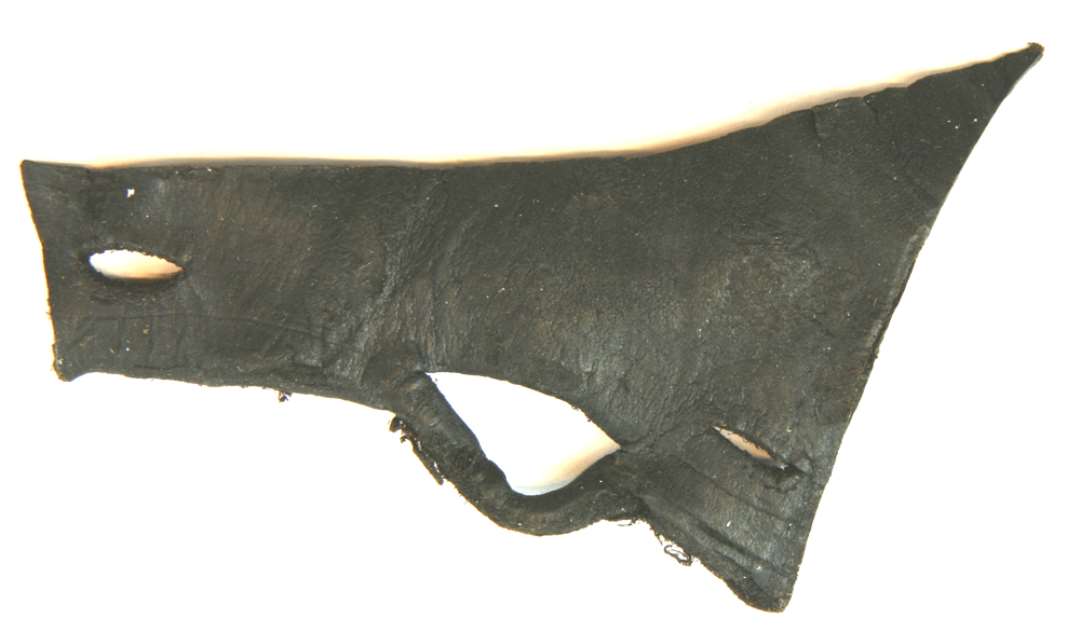 1 stk. forskåret læder af omtrent tresidig form ca. 9,5 - 12 cm. med et større spidsovalt snørehul ca. 1,3 cm. og på hver side heraf to mindre indskårne åbninger ca. 1,5 cm. lange.