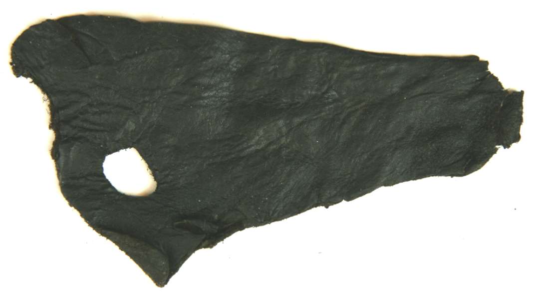 1 stk. forrevet og forskåret læder af omtrent tresidig form ca. 9 x 14 cm. med et ovalt snørehul ca. 1,1 x 1,7 cm.