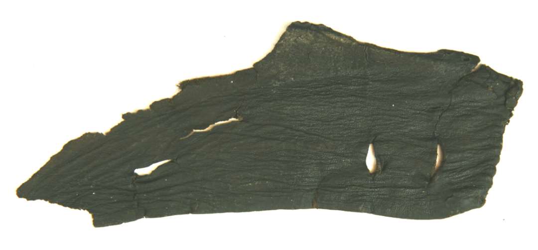 1 fragment af lædersko ca. 6,7 - 16 cm. med svage spor af en sålrand med syhuller samt en lodretgående sømkant. Parallelt med denne findes to snørehulsindskæringer ca. 1,4 og 1,6 cm. lange
