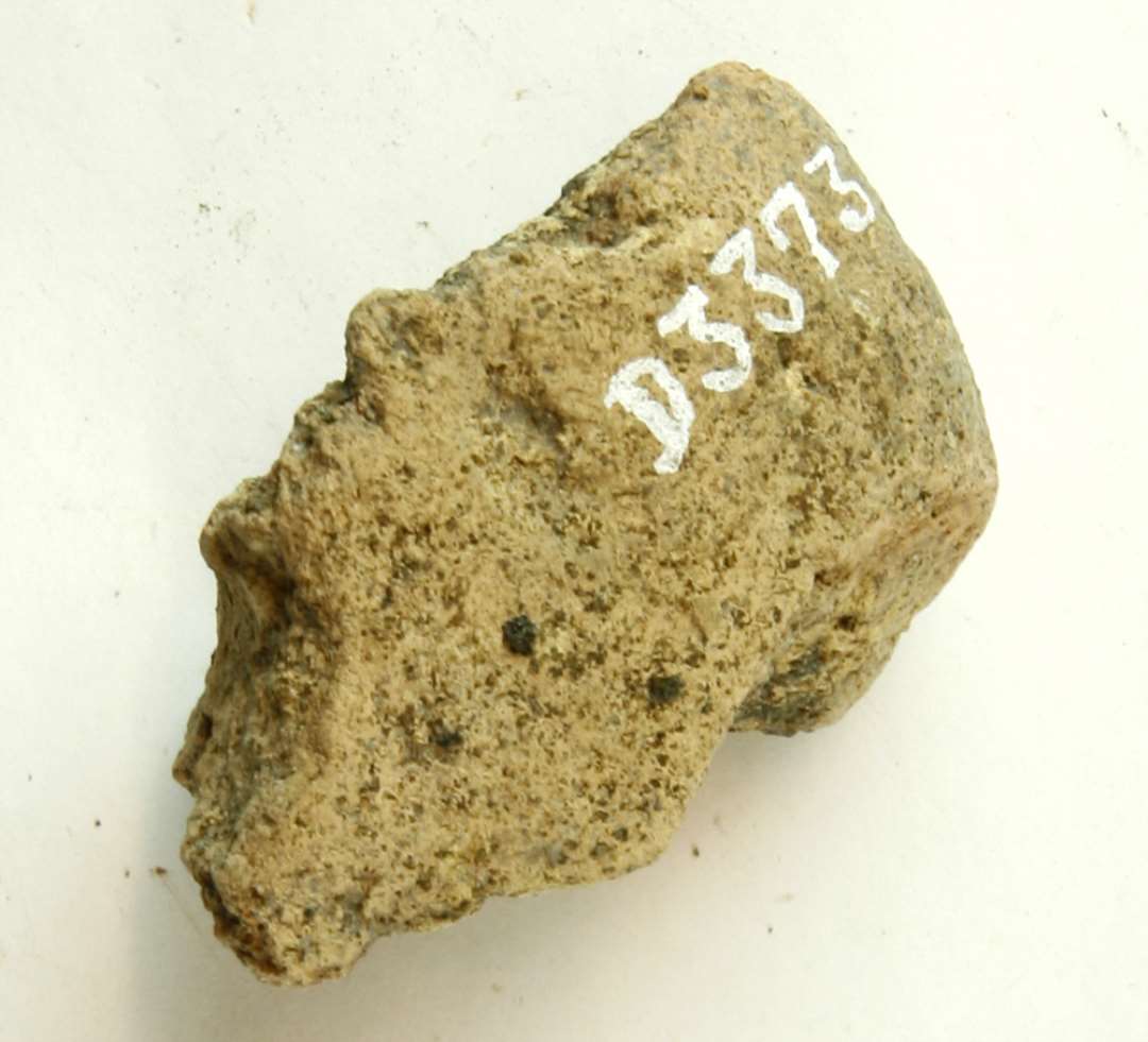 1 fragment af discosformet vævevægt af gråbrunlig brændt lermasse. Største mål: 6,5 cm.