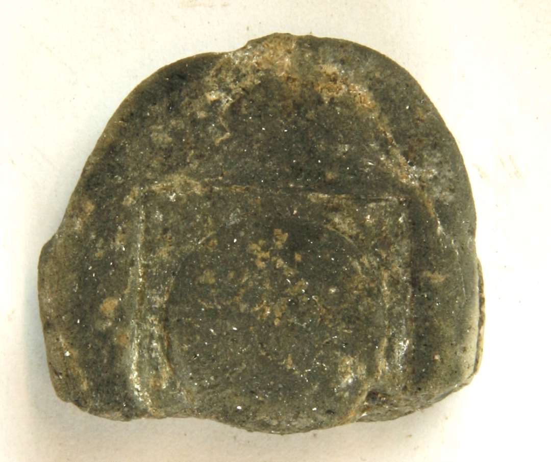 1 fragment af en støbeform af gråbrændt fint magret ler med glimmer i leret. Mål: 4x4,2 cm.
