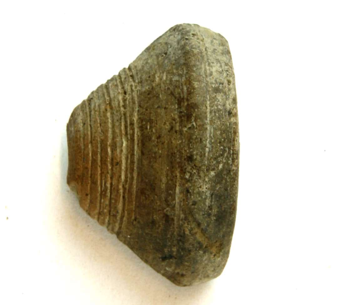 1 fragment af tenvægt af ler. Højde: 2,2 cm., diameter: 4 cm.
