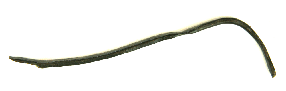 1 smalt tyndt stykke jernbånd, blødt ombøjet i den ene ende. L : ca. 9,5 cm. Br : ca. 0,45 cm. Tyk. ca. 0,2 cm.