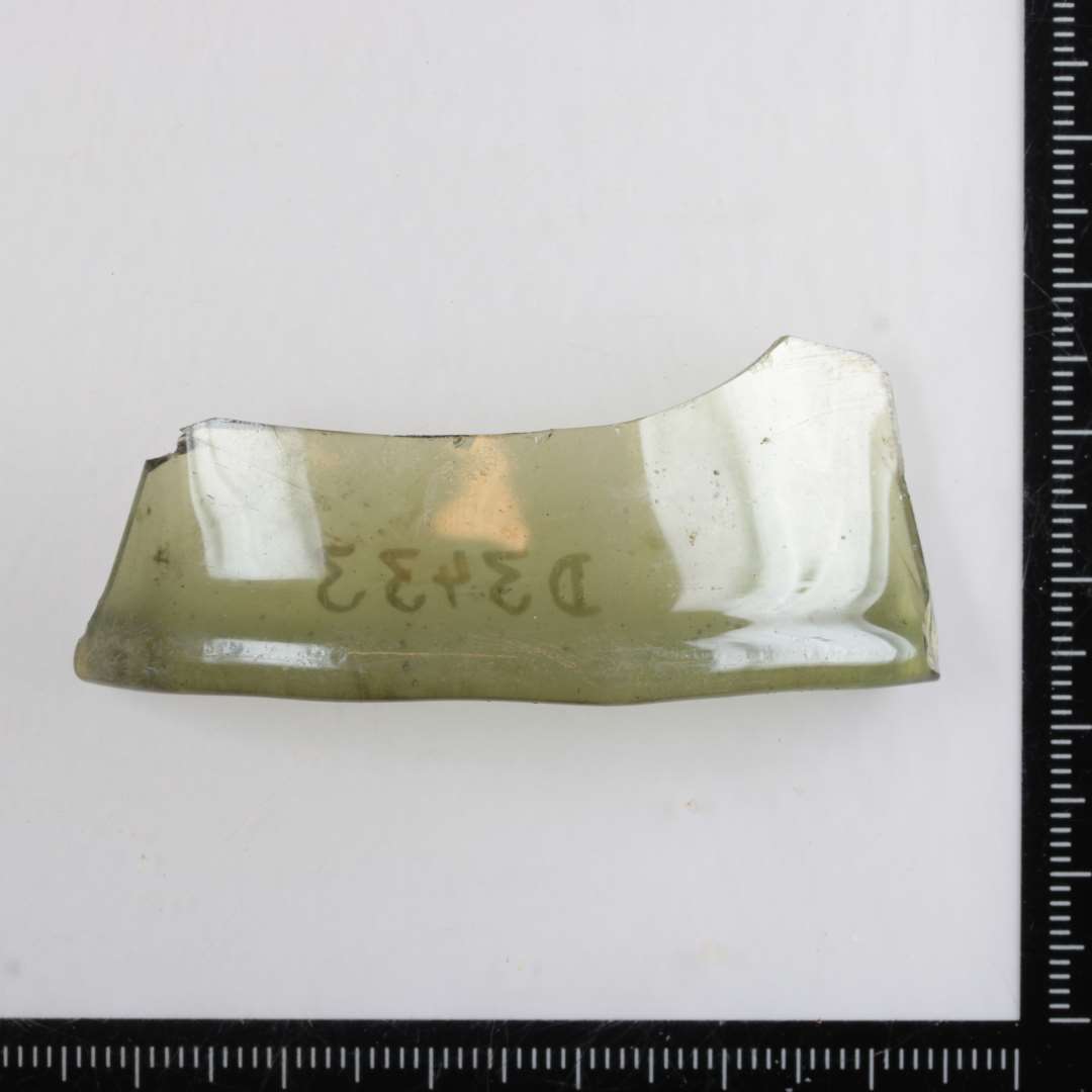 1 randskår af gennemsigtigt grønligt glas med fortykket afrundet rand fra bæger med ottekantet munding.
