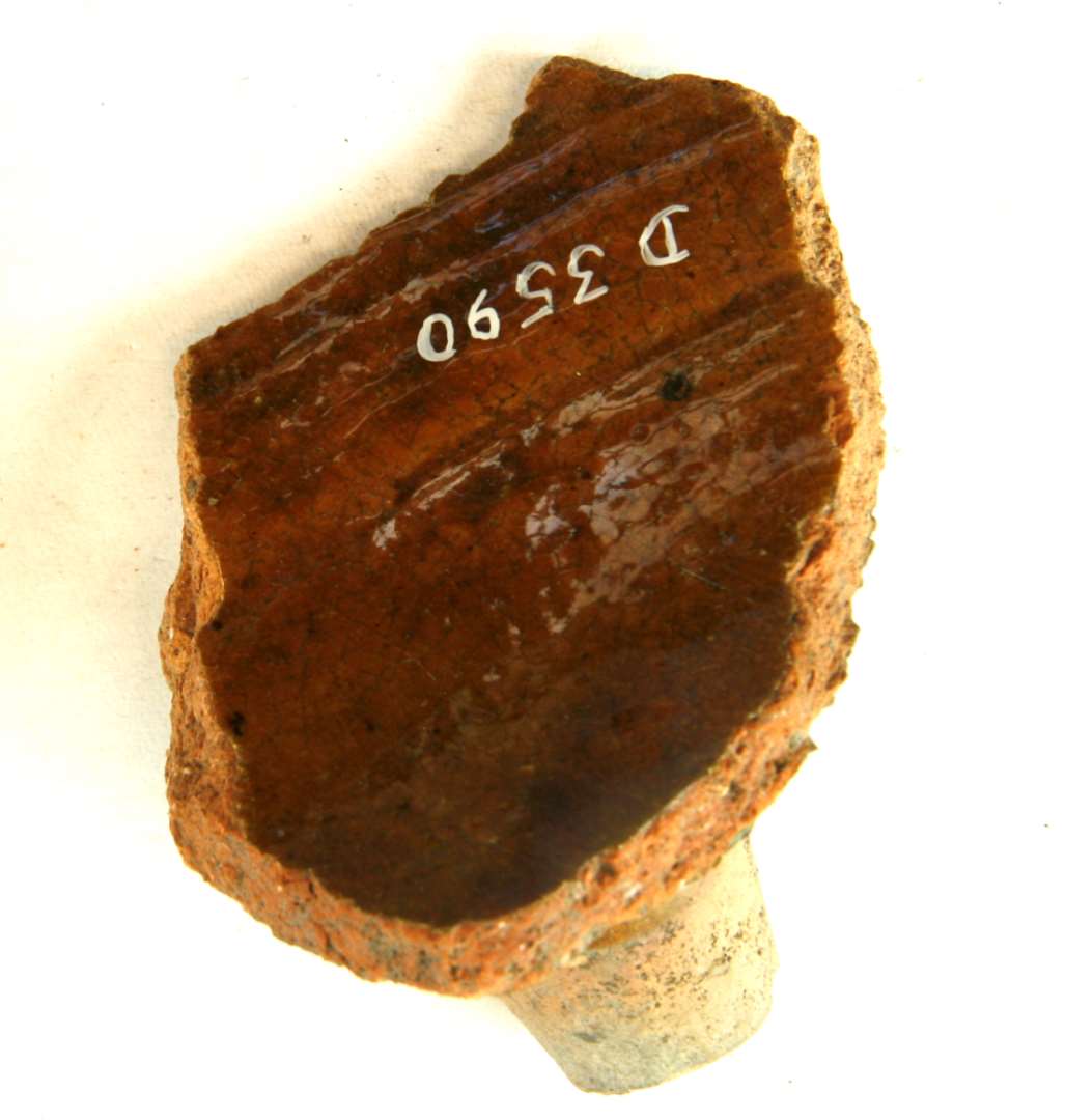 1 bundskår med tå fra stjertpotte af rødbrændt lergods med klar blyglasur, gruppe 1.
