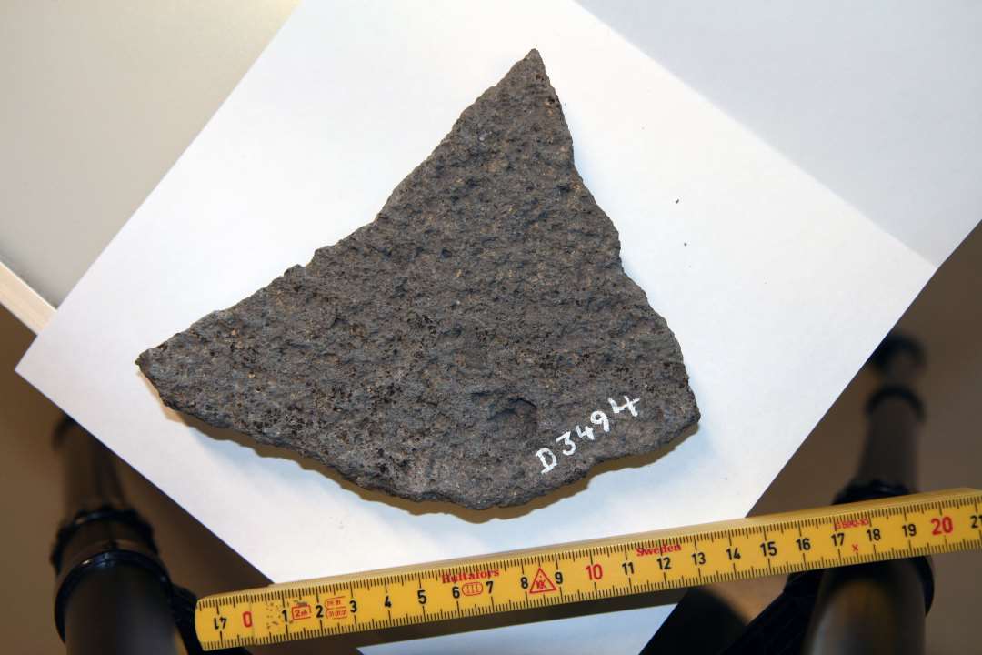 1 fragment af tyndslidt håndkværnsten af basaltlava med grov tilhugning på den ene side og nedslidt, konkav form på den ene side. Største mål ca. 15 X 12,6 cm. tykkelse ca. 2,7 cm.