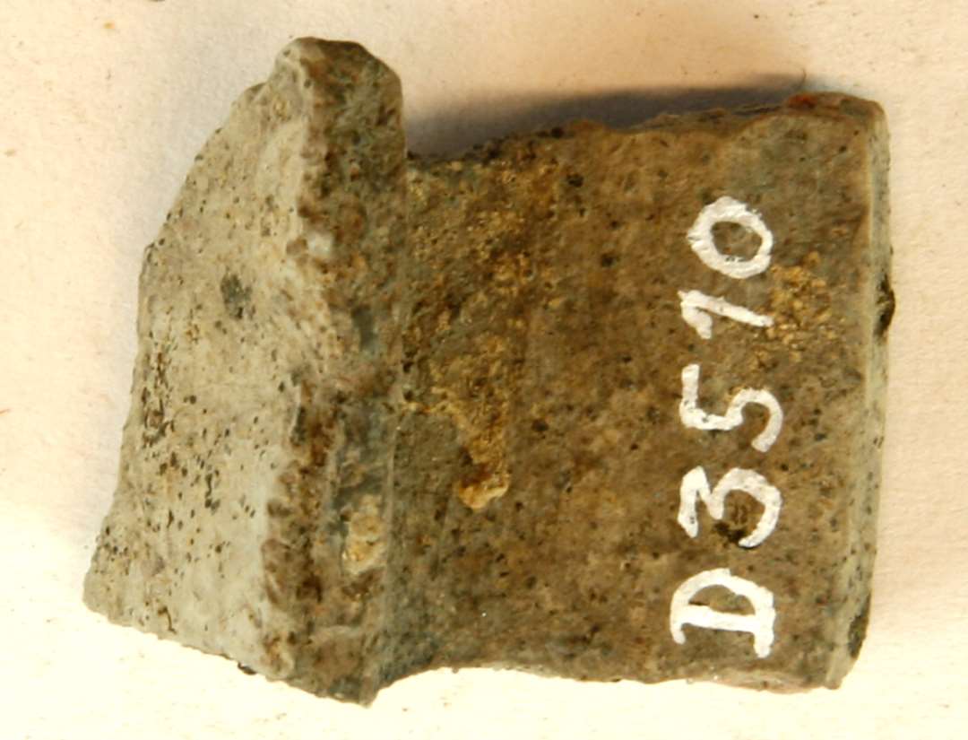 1 fragment af vandret udstående øreflab med svag hulning på den ene side. Magret gråbrunligt lergods, gruppe 4.