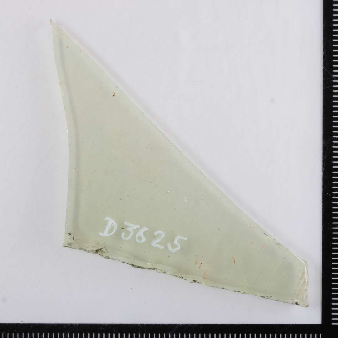 1 fragment af vinduesrude af gennemsigtigt grønligt glas med spor af kantafnapning. Største mål: 8 cm.