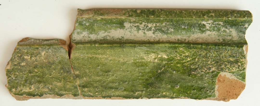 12 fragmenter af kakkelpotter og kakkelmidtfelter af rødbrændt lergods med pibelersbegitning og grøn blyglasur på oversiden, 2 af fragmenterne fremviser udsnit af personer i renæssancetidsdragter. 1 stk. sammenlimet med D3178, 1 stk. sammenlimet med D6581.  