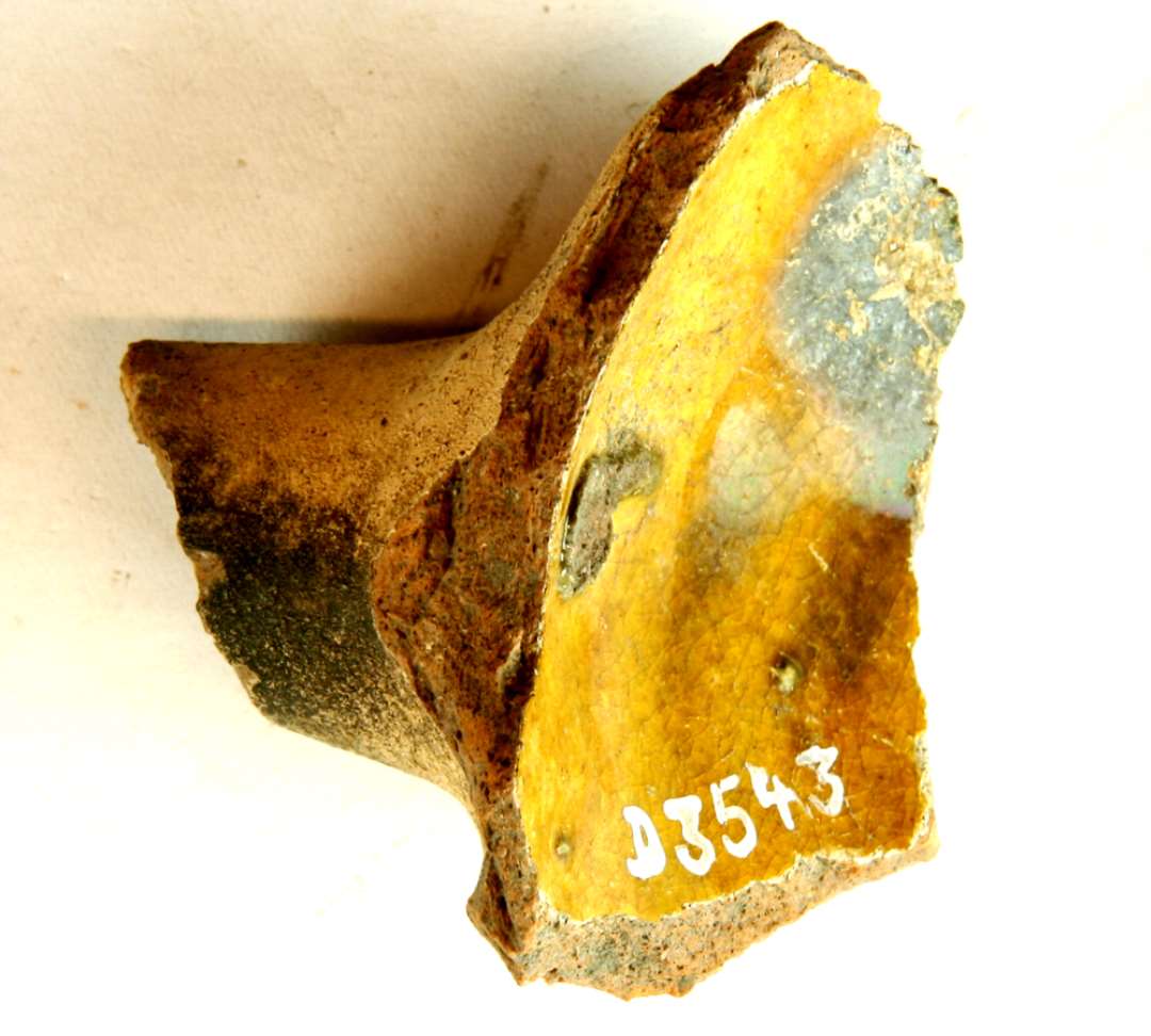 1 fragmenteret stjertpottehank af rødbrændt lergods med pibelersbegitning på ydersiden og karindersiden, der tillige er dækket af klar blyglasur, gruppe 1.