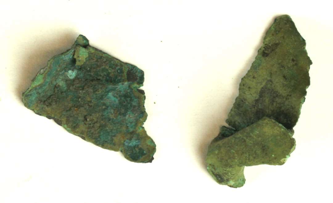 2 mindre fragmenter af lettere krøllet bronzeblik.