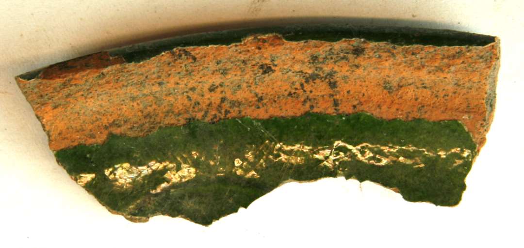 1 mundingsrandskår fra fad af rødbrændt lergods med pibelersbegitning og grøn blyglasur på indersiden, gruppe 1.