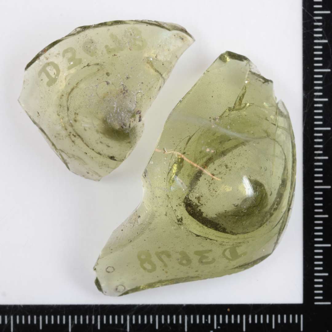 2 fragmenter af opadhvælvede bunde af klart, grønligt glas fra drikkeglas.