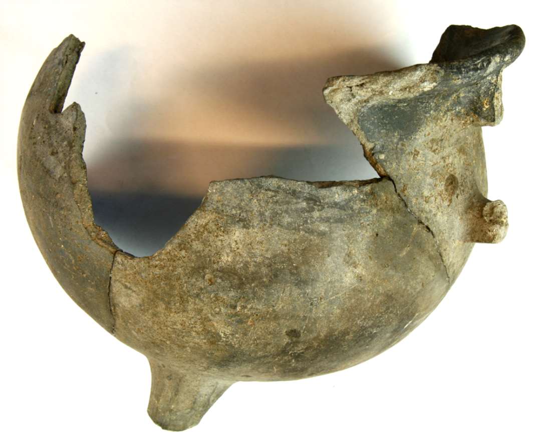 1 fragmenteret jydepotte samlet af flere skår, hvorved rand, hankeansats og en tå ses. Karrets højde er ca. 17 cm. Gruppe o.
