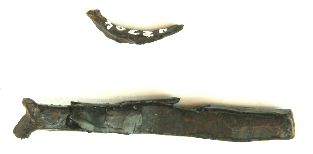 1 massivt let tilspidsende og krummet stykke jern af omtrent kvadratisk tværsnitsform, hvis spidse ende er spaltet i to tynde ombøjede arme, forarbejde til fiskekrog ? L : 5,5 cm.
