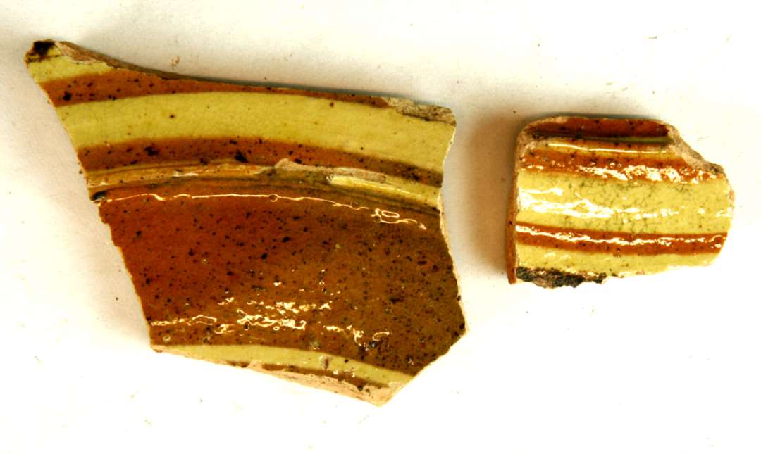 2 sideskår fra hornmalet fad af rødbrændt lergods med dekoration i pibelersbegitning og sortbrun mangan, hvorover klar blyglasur, gruppe 1.