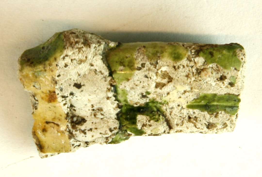 1 mundingsrandskår fra kande ( ? ) af porøst pibelersagtigt gods med afskallet klar og grønlig blyglasur på yders- og indersiden, gruppe 1.