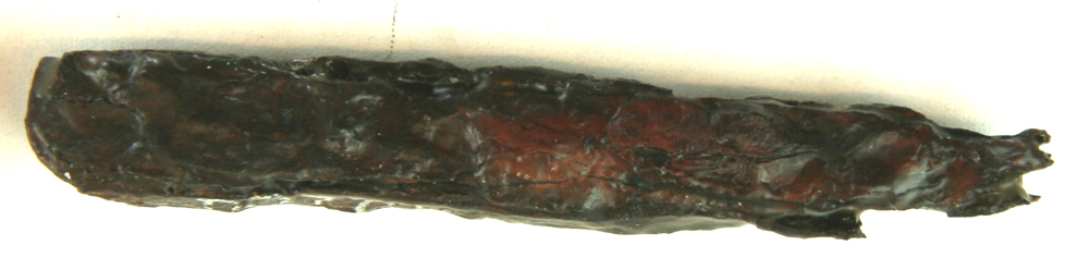 1 stangformet stykke jern af rektangulær tværsnitsform fladt udhamret i en stump bøjet tunge i den ene ende. Længde 8,2 cm. Tværmål 0,8 x 1,1 cm.