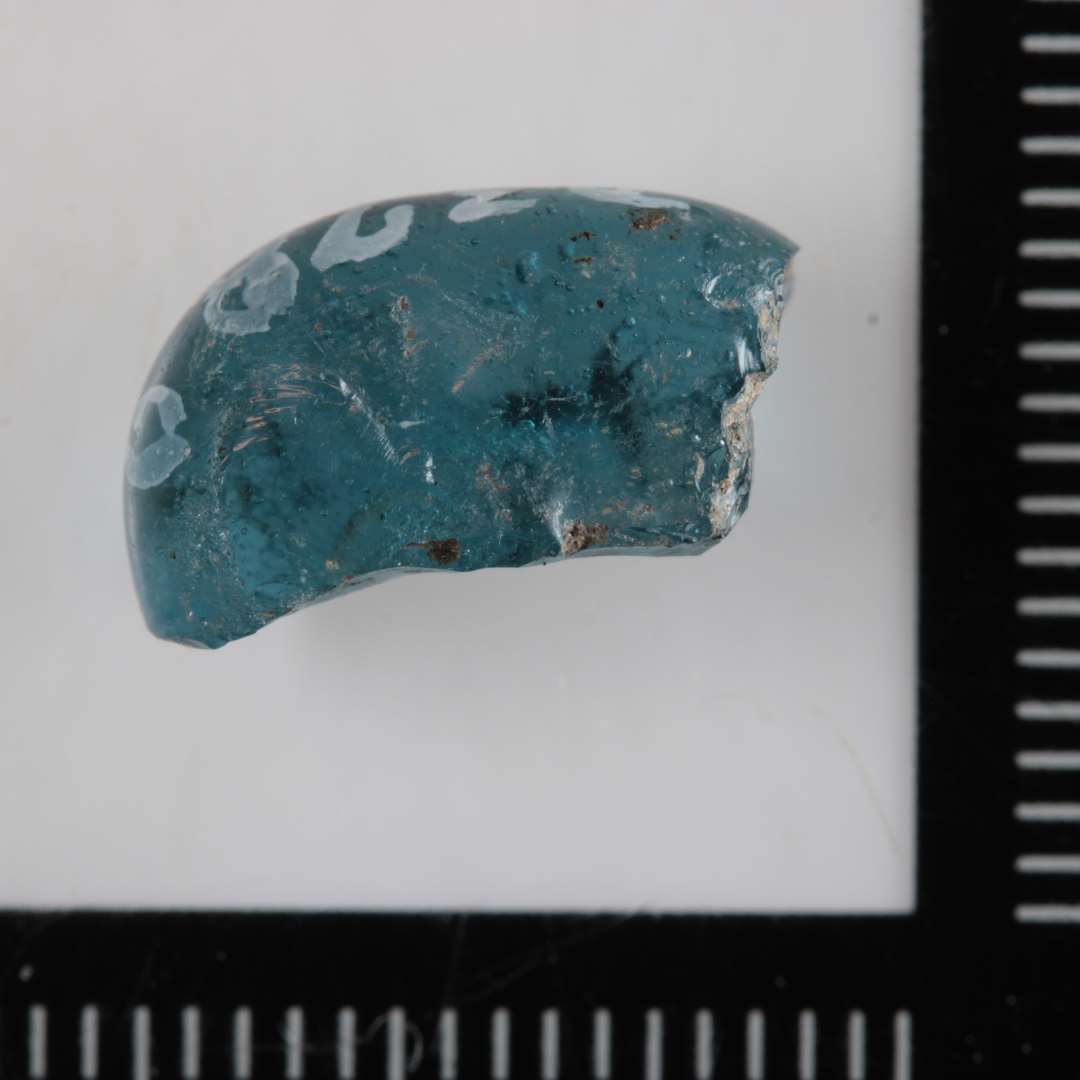 1 lille, klart blåligt fragment af glasperle.