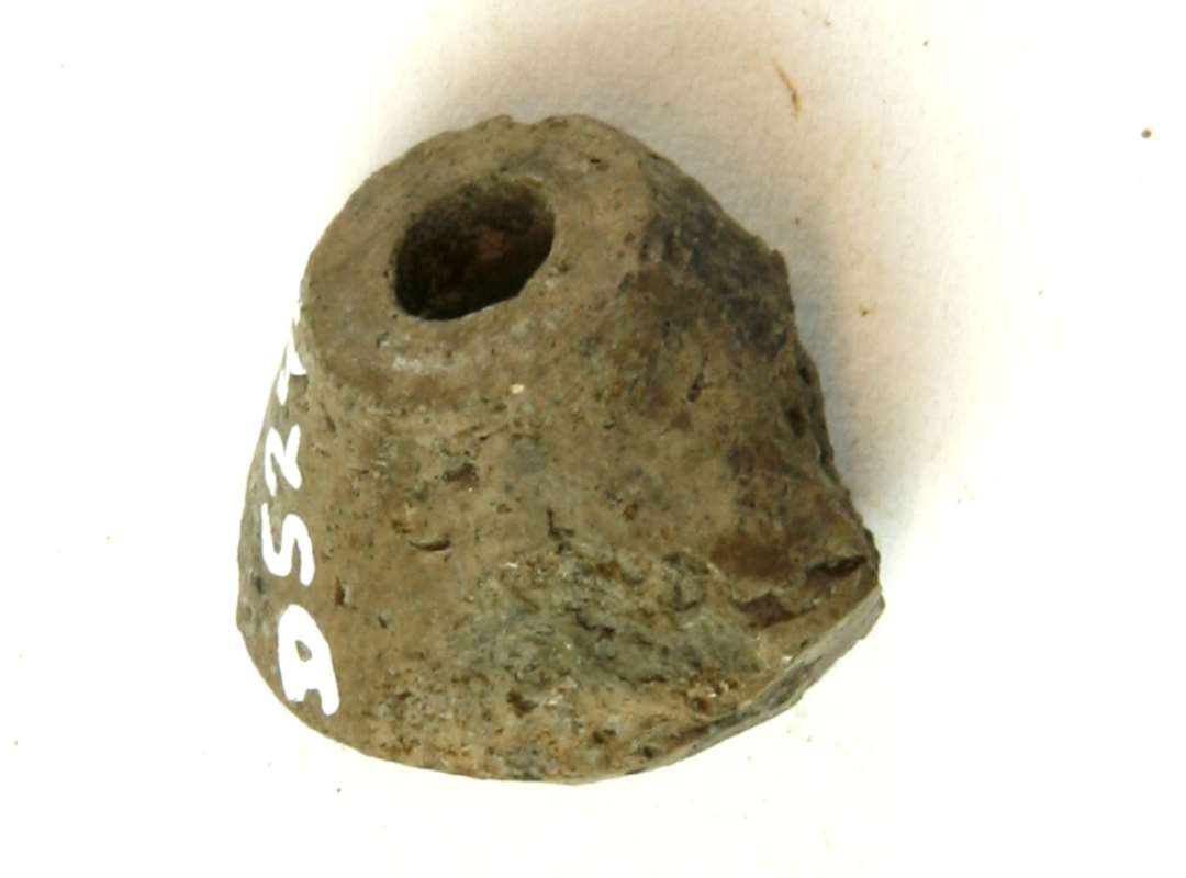 1 fragment af dobbeltkonisk tenvægt af gråbrændt ( hårdt ), fint magret ler, glittet. Højde: 2 cm.