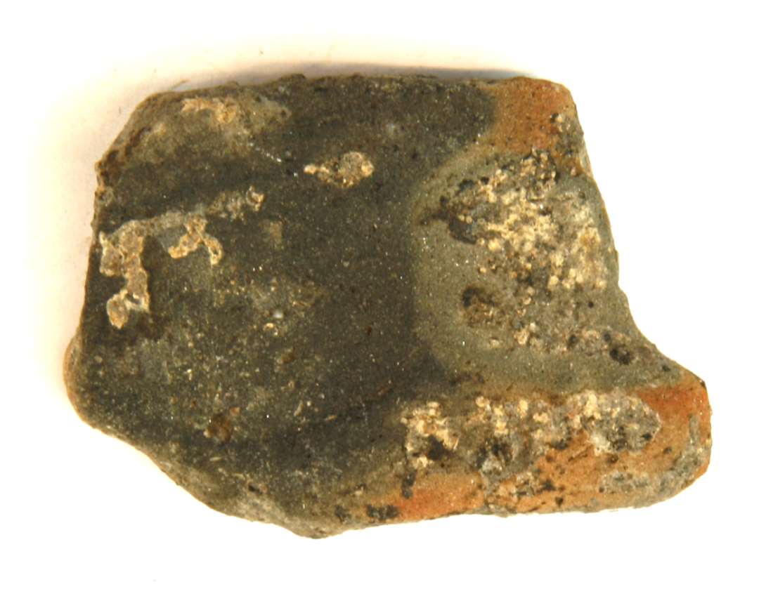 1 fragment af støbeform af finslemmet lergods med brunlig flad yderside og gråsort inderside med fladrundet forsænkning. Længde 5,7 cm. Bredde 4,0 cm. Tykkelse 1,3 cm.