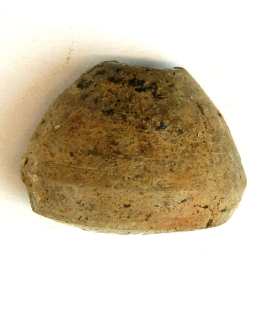 1 tenvægt af finslemmet, gråbrunlig lermasse med delvis glittet overflade. Stykket har konisk form med affaset fod. Højde 2,7 cm. Diameter 3,5 cm.