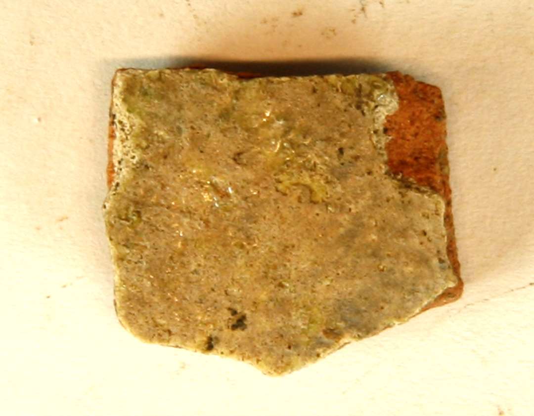 1 sideskår af rødbrændt lergods med pibelersbegitning på ydersiden, hvorover klar til svag grønlig blyglasur, gruppe 1.