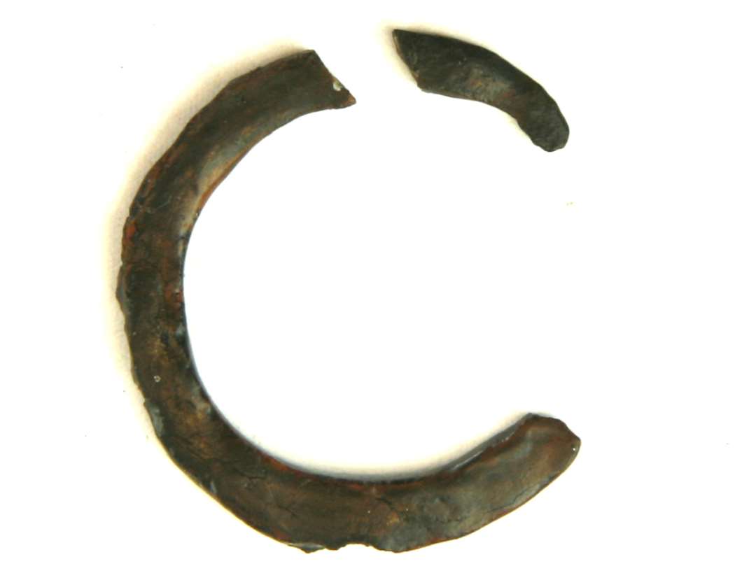 1 jernring, itubrudt, tildannet af et fladt ca. 0,45-0,5 cm. bredt bånd. Ydre diameter ca. 3,5 cm.