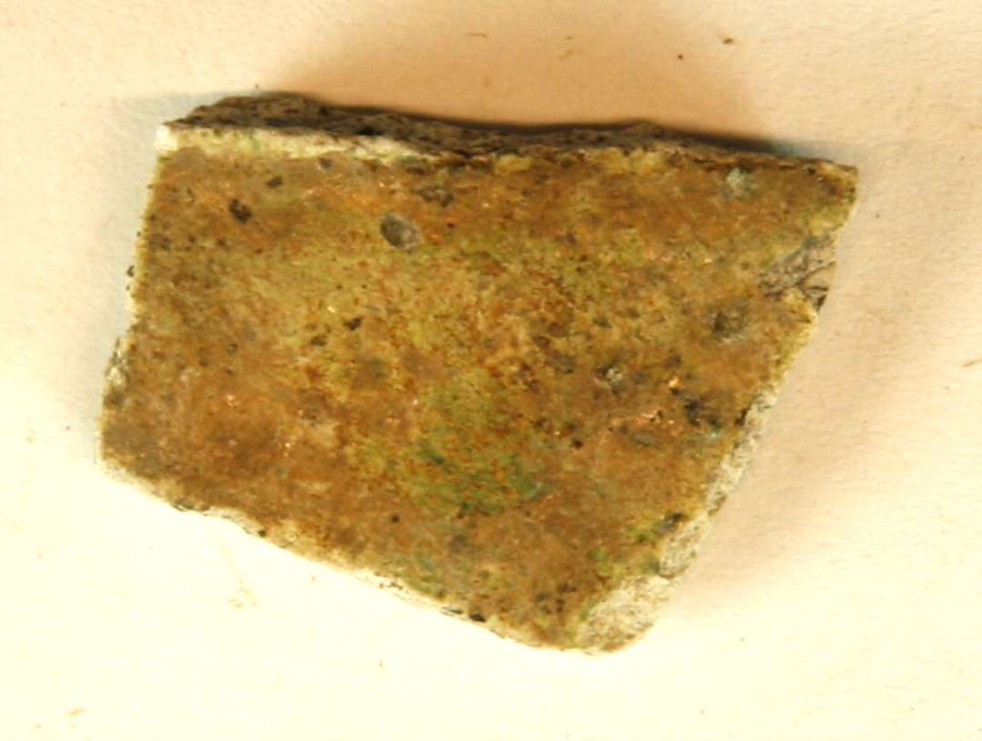 1 sideskår af pibelersagtigt gods med brun/grøn spættet glasur på yder- og inderside, gruppe 1. Muligvis Grøn Rouen.