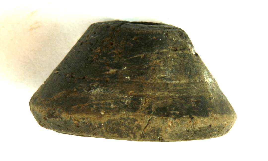 Tenvægt af gråbrunligt, magret lergods af konisk form med affaset fod og afskåret top. Diam. 4,3 cm. Højde ca. 2,3 cm.