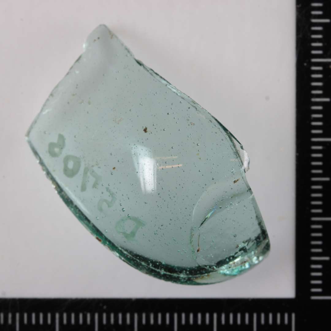 1 bundskår af gennemsigtigt, svagt grønligt glas fra kar ( bæger ) af konisk form med afrundet bund og ganske lille, ujævn bundflade.