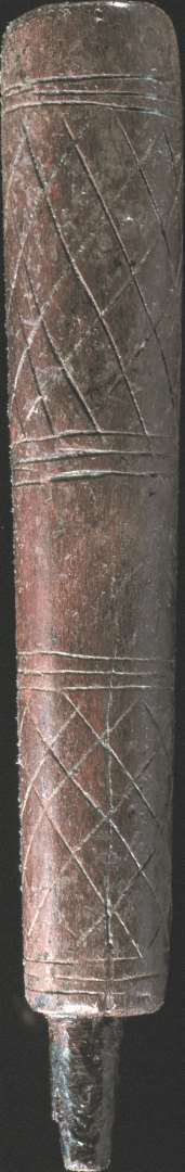 Lædersyl med ornamenteret skaft af hjortetak. Selve jernspidsen er brudt i flere stykker, hvoraf nogle mangler, således at kun en 1,3 cm lang stump sidder tilbage i skaftet. Dette har svagt konisk form med cirkulært tværsnit, ca. 1,6 cm i diameter i skaftenden. 1,25 cm diameter i skafthalsen. Ornamentikken består af indridsede streger, der danner et rudenetmønster afgrænset af tværgående streger ved skaftenderne samt på midten, hvor der findes et udekoreret ca. 1,5 cm. bredt bælte. Total længde 9,75 cm. En stump af jernspidsen afbrækket.