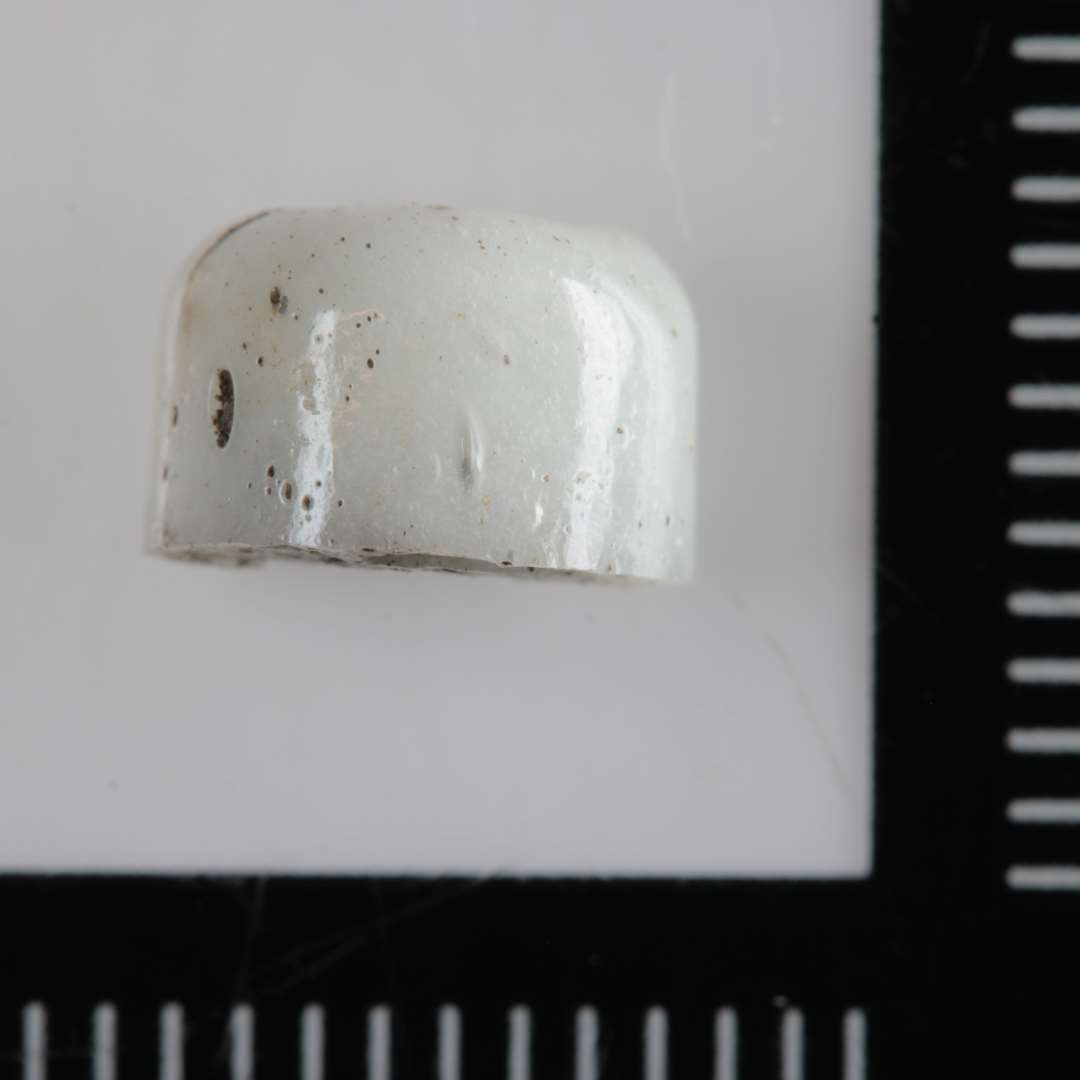 1 fragment af en cylinderformet perle af opakt, hvidt glas.