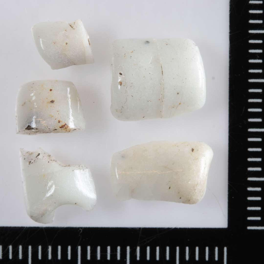 5 fragmenter af cylinderformede perler af hvidligt uigennemsigtigt glas.
