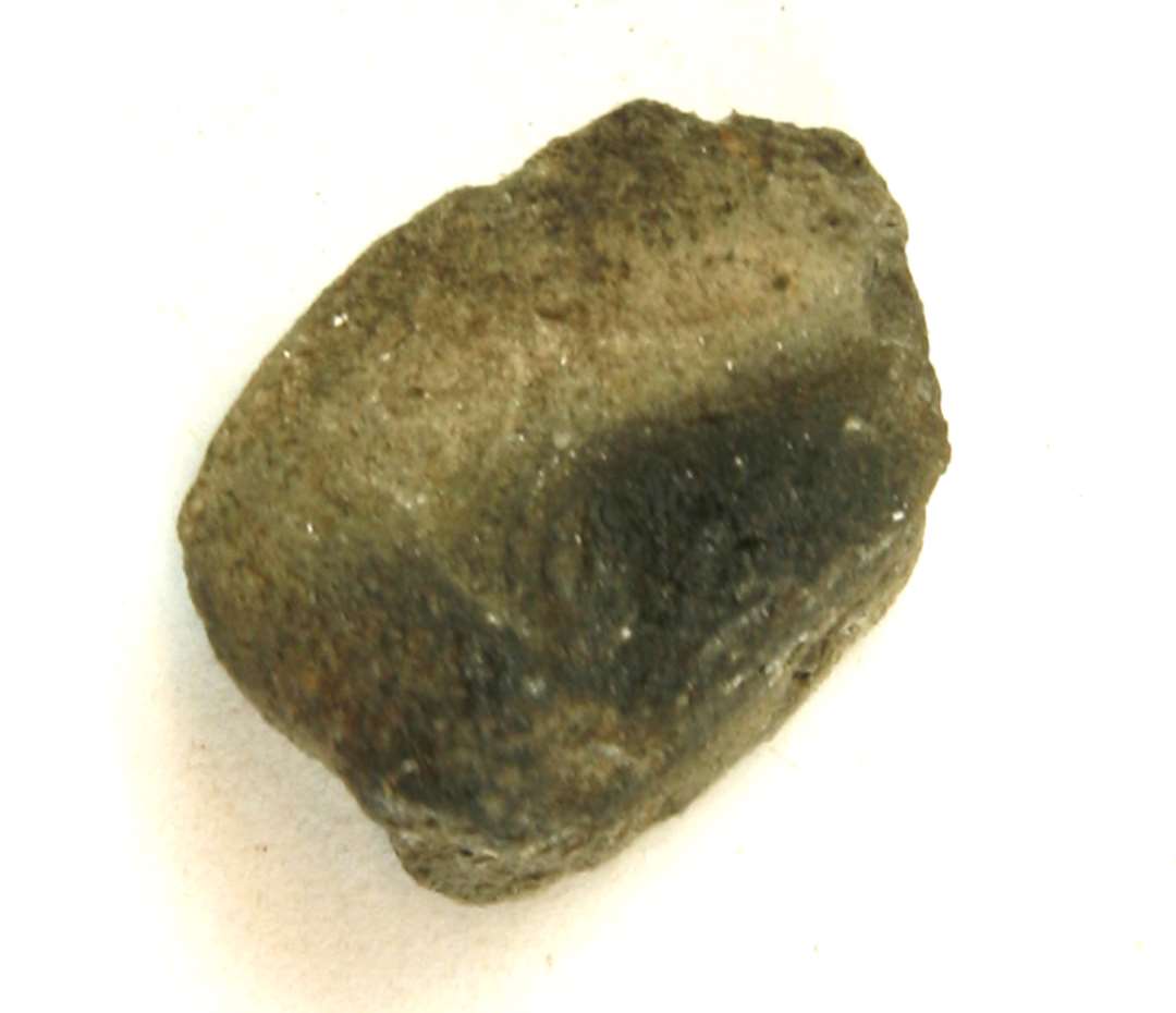 1 fragment af støbeformshalvdel af finslemmet, glimmerblandet lermasse. På indersiden ses rest af oval forsænkning med en art svag rifling i bunden. Mål: 2,5 cm