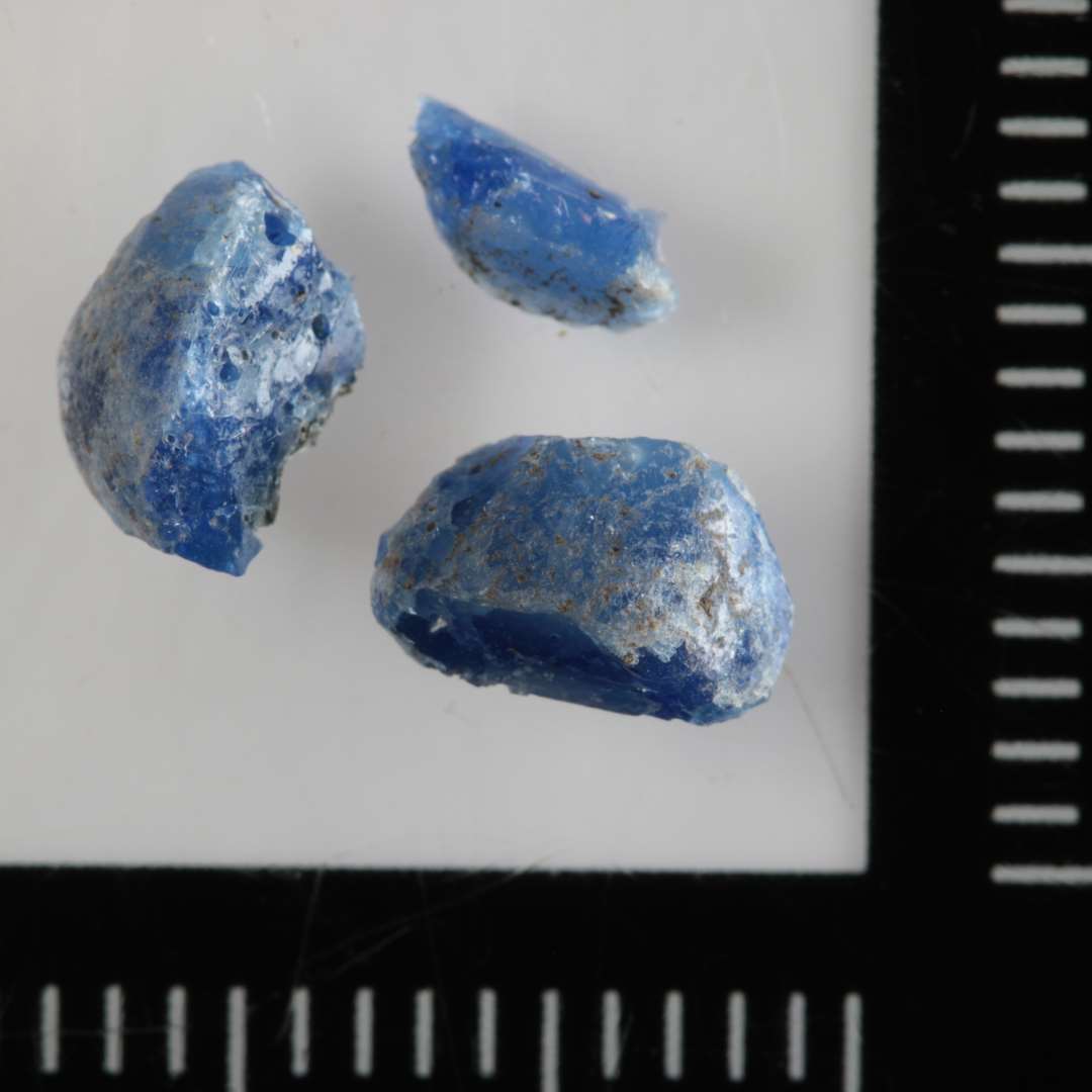 3 fragmenter af en perle af klart, blåt glas.