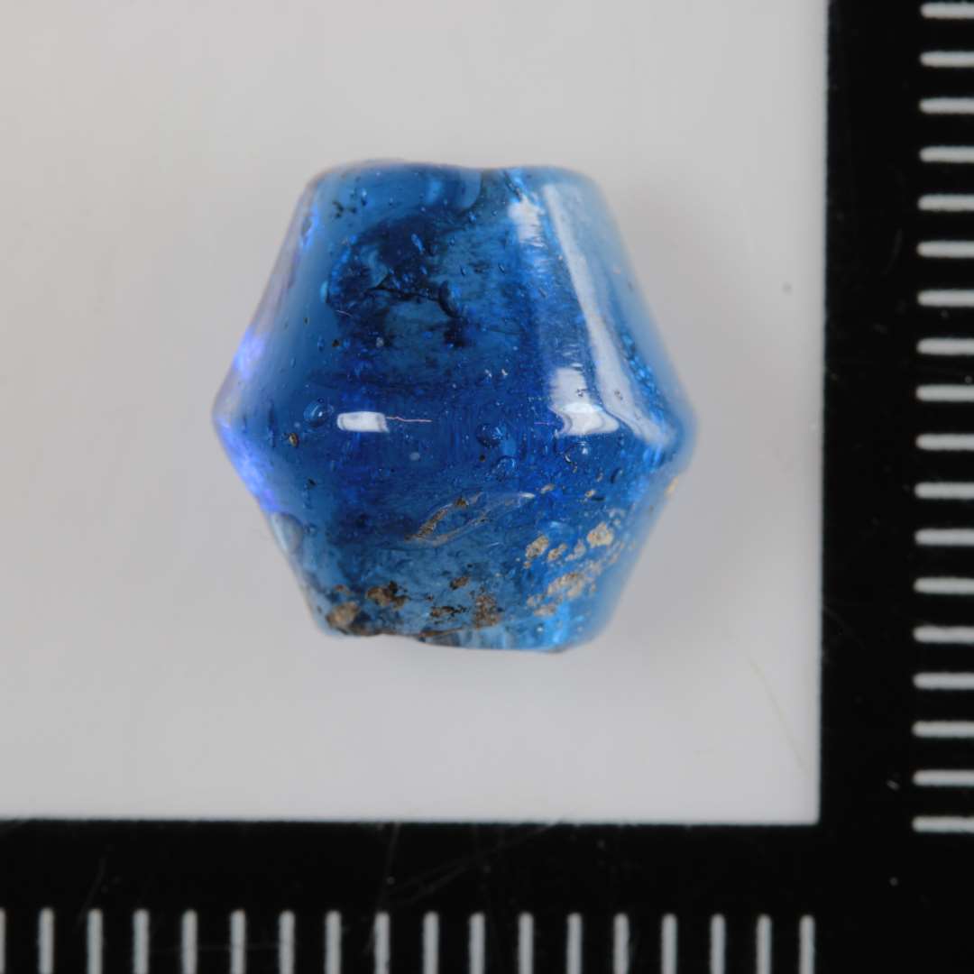 1 perle af dobbeltkonisk facon af klart, blåt glas.